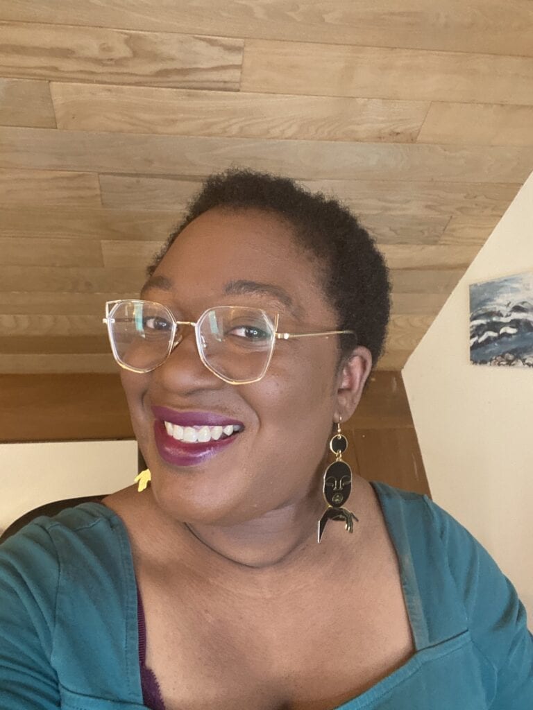 Tinuke Black woman smiling to the camera wearing short hair and afrocentric earrings by Dorcas Creates